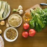 Top view of fresh vegetables and ingredients on a wooden table, ideal for healthy recipes.